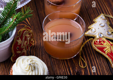 Hausgemachte Weihnachts Cupcakes mit Frischkäse frosting auf hölzernen Hintergrund mit Fichte Zweige in Keramik Eimer und Apfel-Cidre Stockfoto