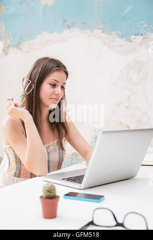 Hübsche junge Frau, die Arbeiten am Laptop im Büro Stockfoto