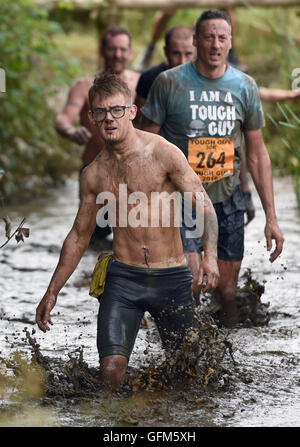 Wettbewerber waten durch einen schlammigen Bach während harter Kerl Brennnessel Krieger 2016 um South Perton Farm in Staffordshire. Stockfoto