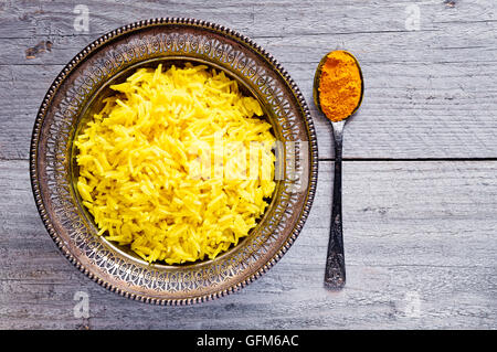 Draufsicht auf eine antike Metallschale mit gekochten Kurkuma Jasmin Reis und Vintage Metall Teelöffel mit pulverförmigen curcumin Stockfoto