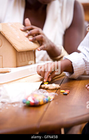 African American Mutter und Kind feiern Sie Weihnachten mit einem Weihnachtsbaum, Lebkuchenhaus und Geschenke. Stockfoto