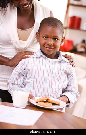 African American Mutter und Kind feiern Sie Weihnachten mit einem Weihnachtsbaum, Lebkuchenhaus und Geschenke. Stockfoto