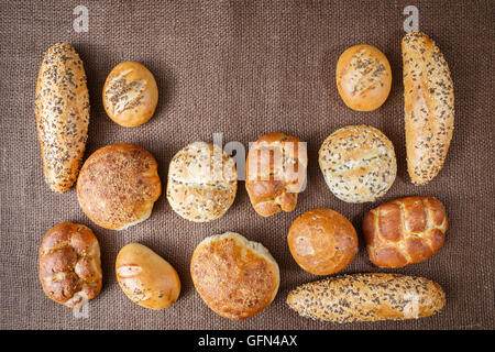 Verschiedene Arten von Vollkorn Brot und Brötchen auf braunem Hintergrund Stockfoto