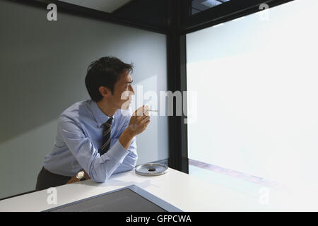 Japanischer Geschäftsmann im Raucherzimmer Stockfoto