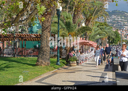 Menschen flanieren und sitzen im Café an der Strandpromenade promenade in Funchal in Madeira, Portugal Stockfoto