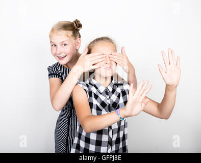 Zwei süße kleine Freundin mit dem Ausdruck ihrer verschiedene Emotionen. Lustige Kinder. Beste Freundinnen verwöhnen und posiert Stockfoto