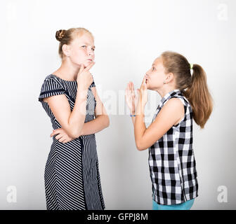 Zwei süße kleine Freundin mit dem Ausdruck ihrer verschiedene Emotionen. Lustige Kinder. Beste Freundinnen verwöhnen und posiert Stockfoto