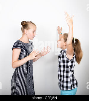 Zwei süße kleine Freundin mit dem Ausdruck ihrer verschiedene Emotionen. Lustige Kinder. Beste Freundinnen verwöhnen und posiert Stockfoto