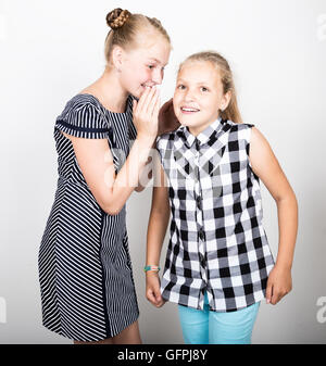 Zwei süße kleine Freundin mit dem Ausdruck ihrer verschiedene Emotionen. Lustige Kinder. Beste Freundinnen verwöhnen und posiert Stockfoto