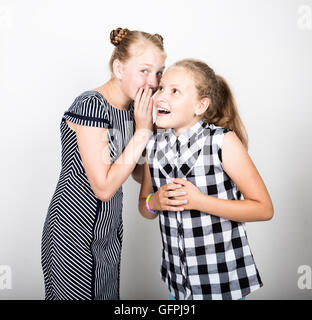 Zwei süße kleine Freundin mit dem Ausdruck ihrer verschiedene Emotionen. Lustige Kinder. Beste Freundinnen verwöhnen und posiert Stockfoto