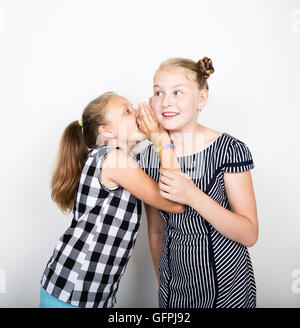 Zwei süße kleine Freundin mit dem Ausdruck ihrer verschiedene Emotionen. Lustige Kinder. Beste Freundinnen verwöhnen und posiert Stockfoto