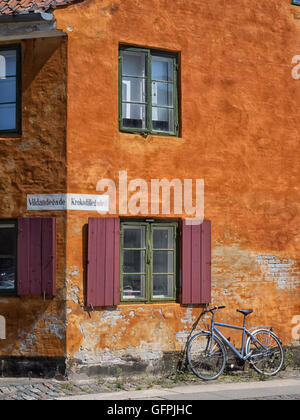 Ecke eines orange Haus in Nyboder mit braunen Fensterläden und ein Fahrrad an die Wand gelehnt. Stockfoto