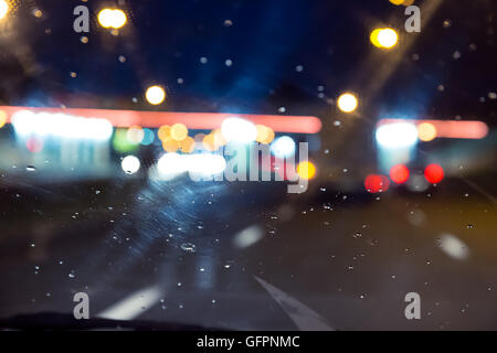 defokussierten Verkehr durch eine Auto-Windschutzscheibe bedeckt Regen gesehen Stockfoto