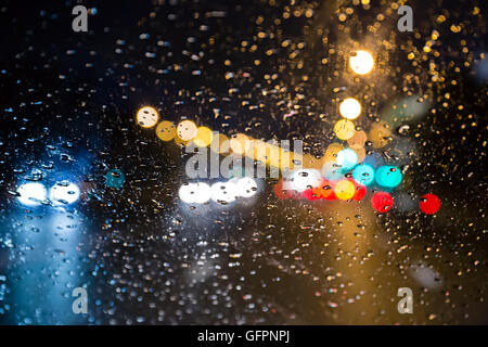 verschwommene Verkehr durch eine Auto-Windschutzscheibe bedeckt Regen gesehen Stockfoto