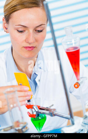 Chemisches Laboratorium Szene: attraktive junge Studentin Wissenschaftler beobachten die blaue Anzeige Farbverschiebung nach der Lösung Stockfoto