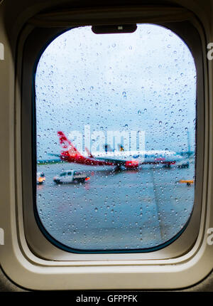 Blick auf das Flugzeug durch das Fenster mit Regentropfen Stockfoto