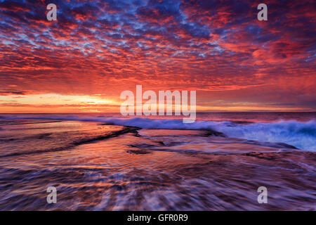 aufgehenden Sonne über Felsen Bett Sydney pazifischen Küste in der Nähe von Mona Vale Strand. Goldenes Licht und Stunde machen dieses schöne natürliche Stockfoto