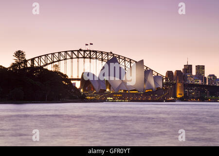 Sydney, Australien, 1. Juli 2016 - Sydney Oper Reiterdorf und Hafen Brücke bei Rosa Sonnenuntergang beleuchtet. Berühmte moderne Architektur o Stockfoto