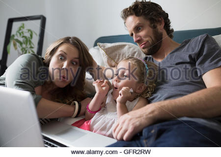 Junge Familie Grimassen video-Chats mit Laptop am Bett