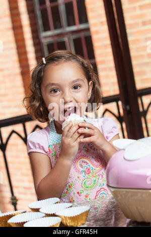 Kleines Mädchen vorbereiten und Essen Muffins Stockfoto