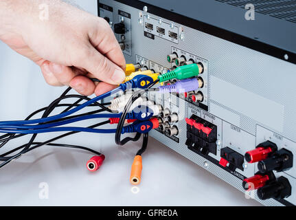 Foto von Hand Anschlussleitungen an einen AV-Receiver auf weißem Hintergrund Stockfoto