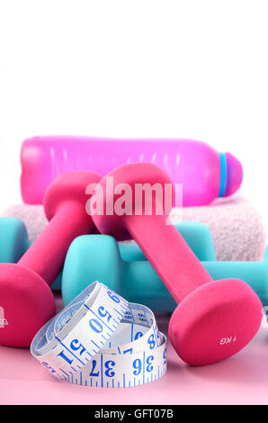 Gesundheit und Fitness-Konzept mit rosa und blauen Hanteln und Zubehör auf einem rosa Holztisch. Stockfoto