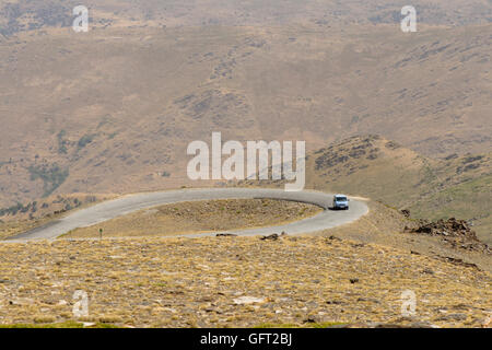 Kurvenreiche Straße und Auto in kargen Landschaft Berge der Sierra Nevada, Granada, Spanien. Stockfoto