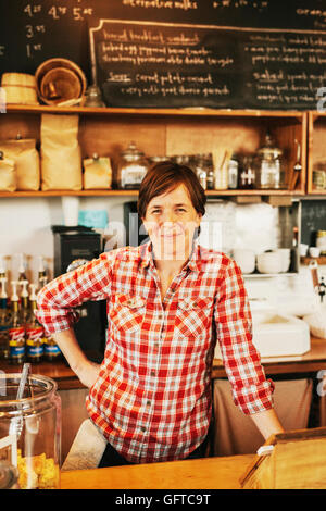 Eine Frau in einem Café hinter der Theke lächelnd Eigentümer Stockfoto