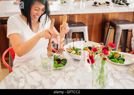 Verlässt eine Frau mit Salatbesteck, laden ihre Teller mit frischem Salat Stockfoto