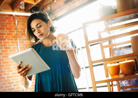 Junge Frau in einem Geschäft mit einem digital-Tablette und eine Duftkerze Stockfoto