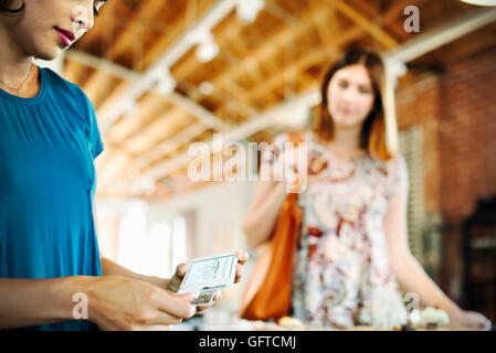 Zwei junge Frauen in einem Geschäft mit einem Credit-Kartenleser Stockfoto