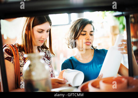 Zwei junge Frauen in einem Geschäft, Blick auf eine weiße Keramik Vase und Becher Stockfoto