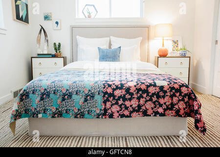 Ein Schlafzimmer in einem Apartment mit einem Doppelbett bedeckt mit einem gepatchten Quilt mit Patchwork und florale Muster Retro-look Stockfoto