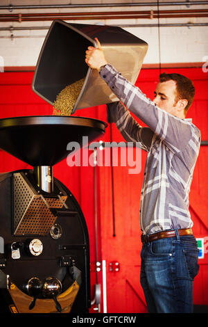 Ein Mann Gießen Kaffeebohnen in einen Trichter in eine Kaffeemühle Stockfoto