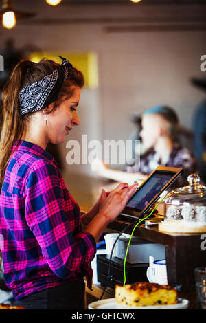 Eine Frau hinter der Theke über den Touchscreen auf der Kasse arbeiten Stockfoto
