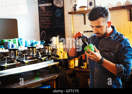 Ein Mann bereitet Cappuccino-Schaum-Muster in eine Kaffeetasse zu schaffen Stockfoto