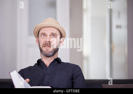 Weißen männlichen Mann mit Buch sitzen und blickte Exemplar Stockfoto