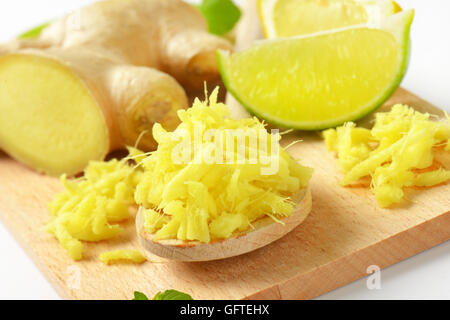 Detail des ganzen und geriebenem frischem Ingwer mit Kalk auf Holzbrett Stockfoto