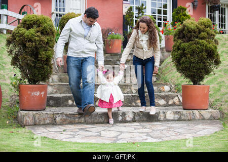 Eltern lehren ihre baby girl, wie man zu Fuß die Treppe hinunter Stockfoto