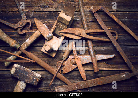 Grunge alte verrostete Werkzeuge auf einer hölzernen Hintergrundverarbeitung (Prozess-) Stockfoto