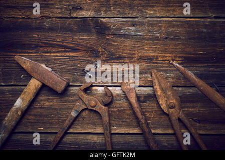 Grunge alte verrostete Werkzeuge auf einer hölzernen Hintergrundverarbeitung (Prozess-) Stockfoto