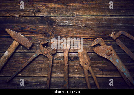 Grunge alte verrostete Werkzeuge auf einer hölzernen Hintergrundverarbeitung (Prozess-) Stockfoto