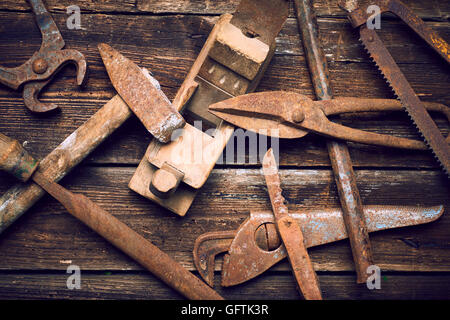 Grunge alte verrostete Werkzeuge auf einer hölzernen Hintergrundverarbeitung (Prozess-) Stockfoto