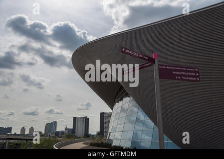 Das geschwungene Dach der Olympic Aquatic Center gegen eine stimmungsvolle Himmel.  Wegweiser für andere Parkanlagen im Vordergrund Stockfoto