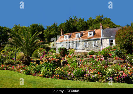 Ferienhaus Blumenbeeten und Rasen gegen blauen Himmel Stockfoto