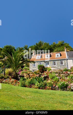 Ferienhaus Blumenbeeten und Rasen gegen blauen Himmel Stockfoto