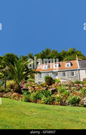 Ferienhaus Blumenbeeten und Rasen gegen blauen Himmel Stockfoto