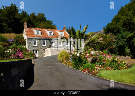 Ferienhaus Blumenbeeten und Rasen gegen blauen Himmel Stockfoto