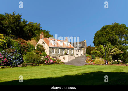 Ferienhaus Blumenbeeten und Rasen gegen blauen Himmel Stockfoto