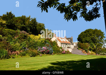 Ferienhaus Blumenbeeten und Rasen gegen blauen Himmel Stockfoto